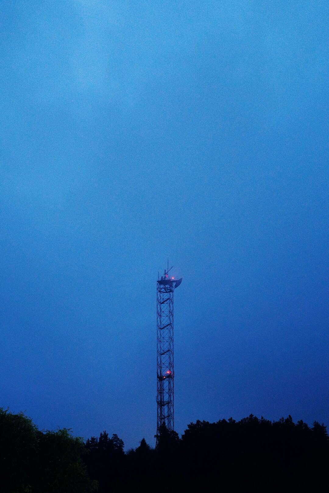 Radio broadcasting tower against blue sky at dusk